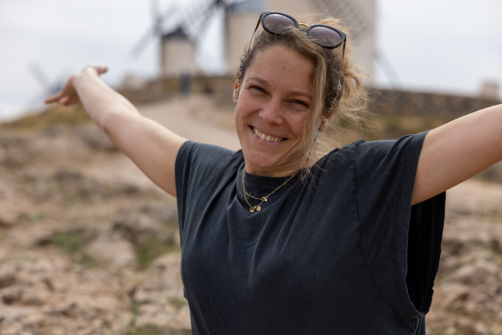Francesca Schori mit weit ausgebreiteten Armen fröhlich und herzlich in Kamera lächelnd.