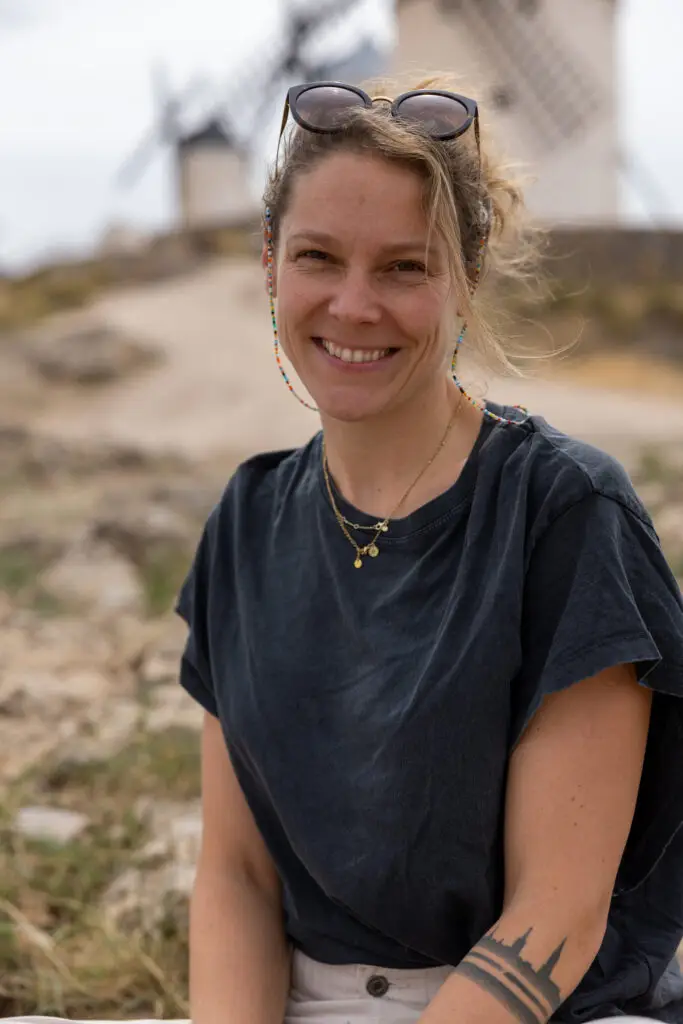 Francesca Schori sitzend vor Windmühlen in die Kamera lächelnd