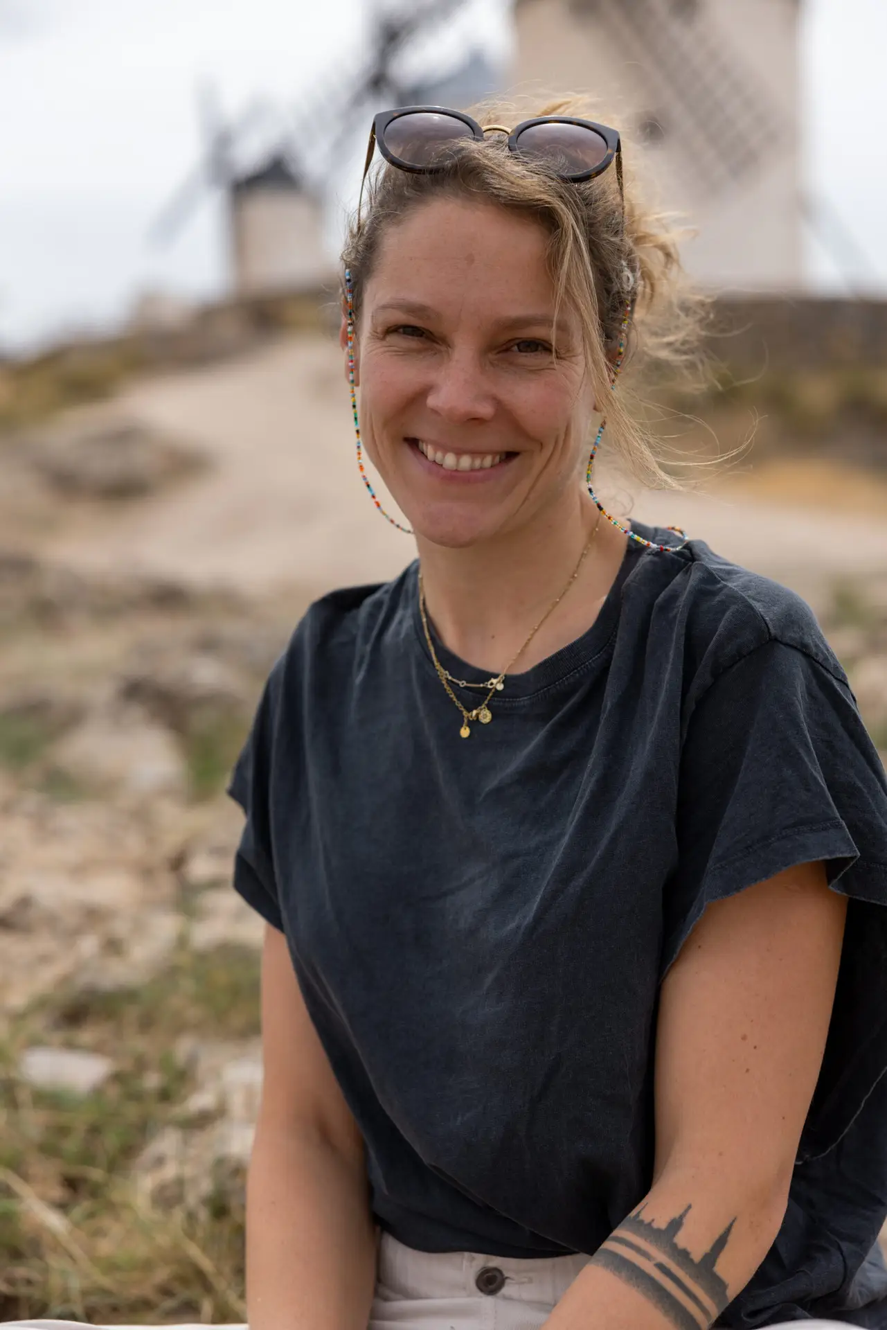 Francesca Schori sitzend vor Windmühlen in die Kamera lächelnd