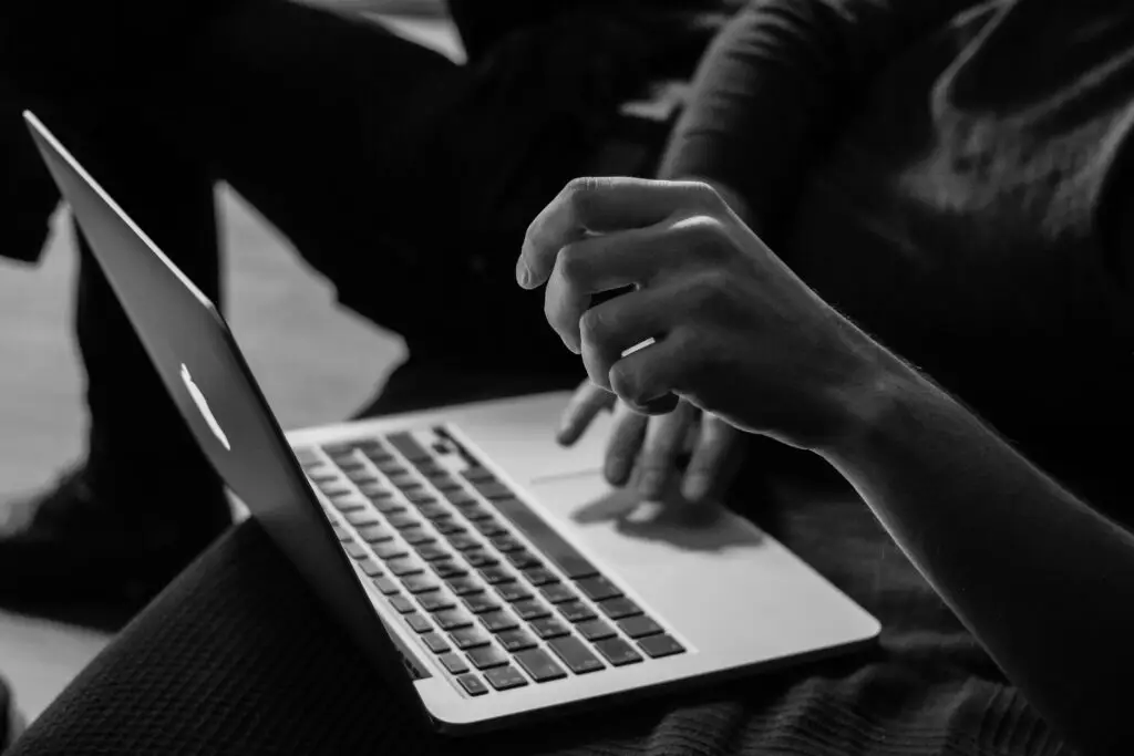 Virtuelle Assistenz oder Person tippt auf iMac schwarz-weiss-Foto von Sergey Zolkin auf Unsplash
