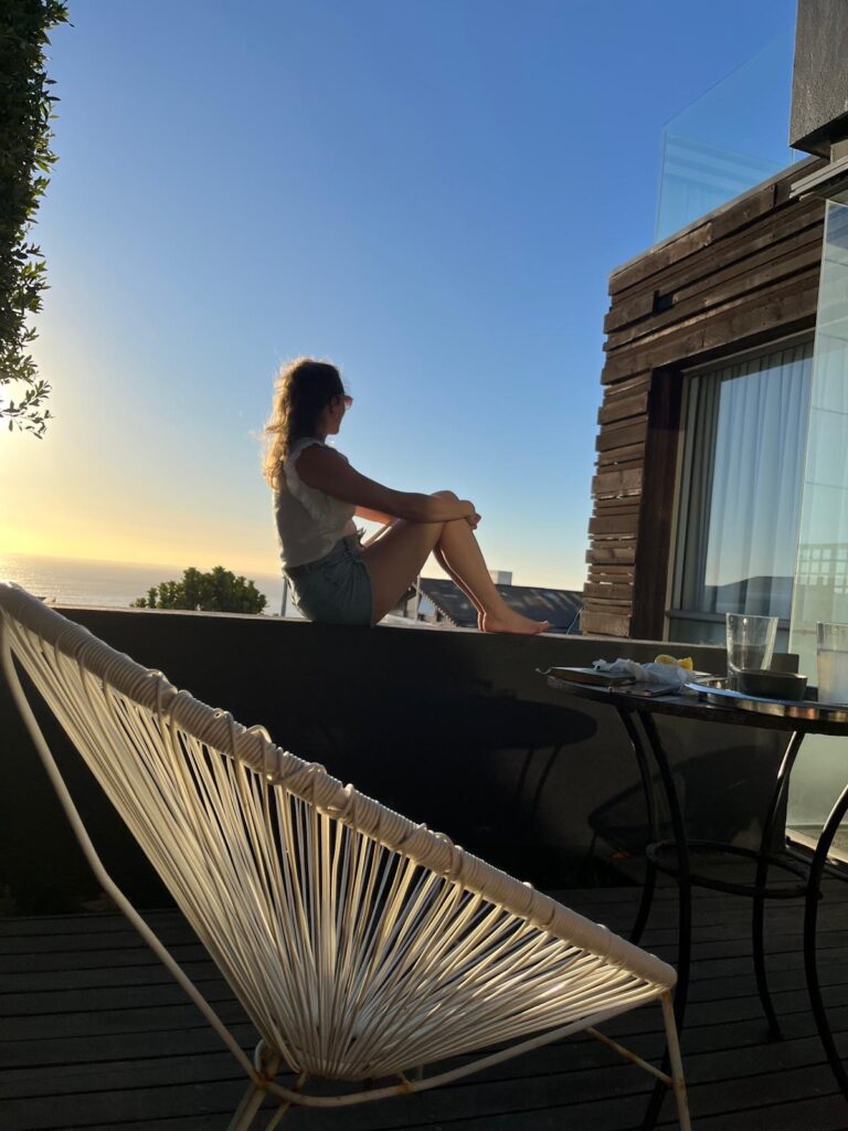 Francesca Schori sitzend auf einer Mauer in die Ferne schauend.