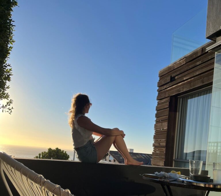 Francesca Schori sitzend auf einer Mauer in die Ferne schauend.