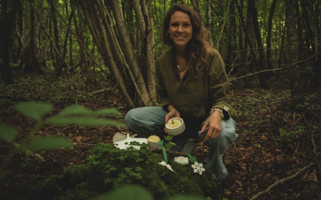 Francesca Schori im Wald sitzend mit ihren Kerzen und natürlich hergestellten Produkten